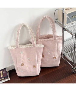Detail of pink plush tote bags with white fleece lining and cute festive embroidery