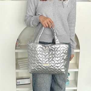 Detail of silver heart-quilted tote bag featuring metallic finish and thick handles