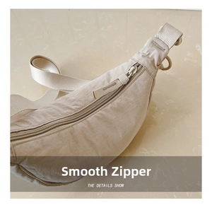 Detail of smooth zipper closure and adjustable strap on beige nylon crossbody bag