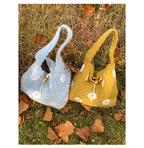 Detail of plush knitted floral tote bag featuring wooden toggle button and drawstring closure