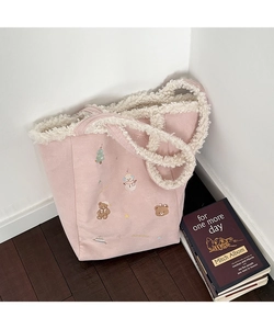 Detail of pink plush tote bag featuring festive Christmas embroidery and soft faux fur trim