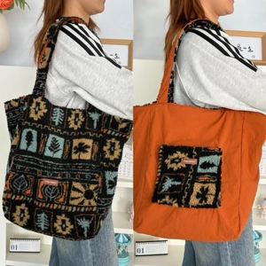 Detail of reversible plush tote bag showing colorful folk pattern and orange fabric side