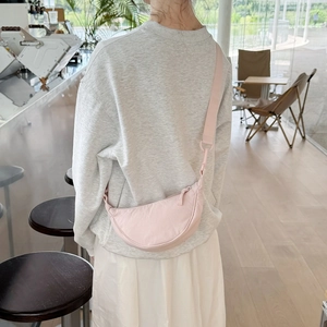 Detail of light pink adjustable half-moon crossbody bag in water-resistant nylon fabric
