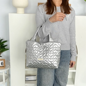 Close-up of heart-shaped quilted pattern on silver metallic portable handbag surface