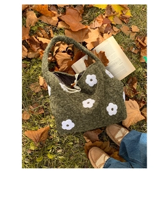 Detailed macro shot of dark green plush tote bag with white floral embroidery and drawstring