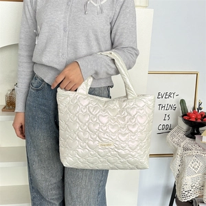 Chic pearlescent white heart quilted tote bag featuring a metallic sheen and wide handle