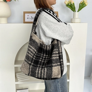 Close-up of fluffy black and beige checkered tote bag shown on model for autumn winter