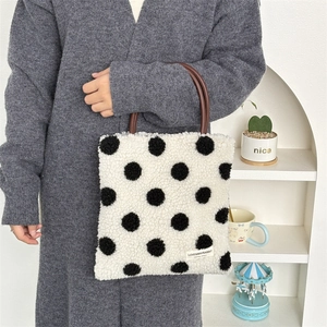 Detail of plush polka dot tote bag with brown leather handles and woven brand label