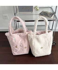 Detail of pink embroidered tote and white sherpa plush shoulder bag for winter styling