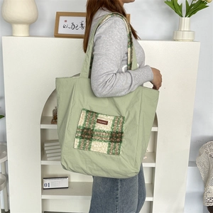 Detail view of large green plush tote bag showing check pattern pocket and shoulder strap