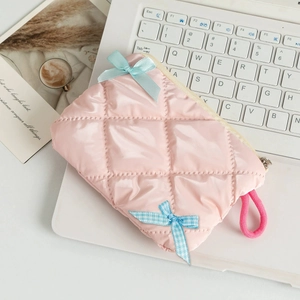 Detail of pink quilted cosmetic bag with blue bows and strap on a laptop keyboard