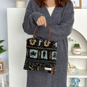 Close-up of plush tote bag featuring blue maple leaf patterns and brown round handles