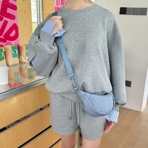 Detail of light blue nylon crescent crossbody bag styled with casual grey lounge set