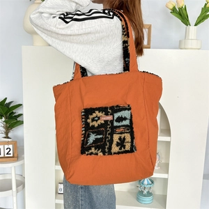 Detail of orange nylon tote bag featuring a fleece ethnic pattern and brand label