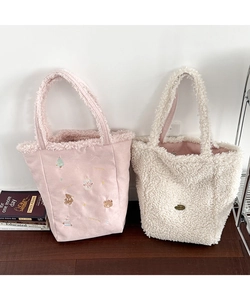 Detail of plush tote bags with cute seasonal embroidery and soft white fleece texture