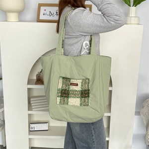 Detail view of the plush checkered pocket and brand label on a green tote bag