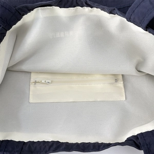 Detail of the navy blue tote bag interior with inner zipper pocket and off-white lining
