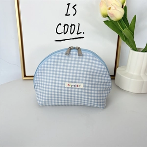 Detail of blue plaid shell cosmetic bag with silver double zippers and brand label