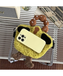 Detail of cute green plush phone bag with brown handles and shoulder strap next to a phone