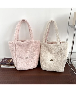 Detailed macro view of soft plush faux shearling texture on pink and beige tote bags