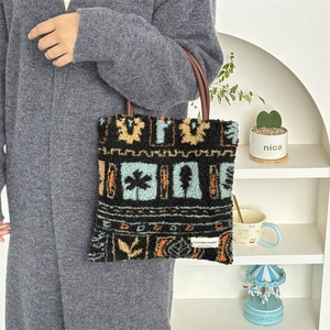 Detail of plush tote bag with ethnic print, leather handles and brand label on side