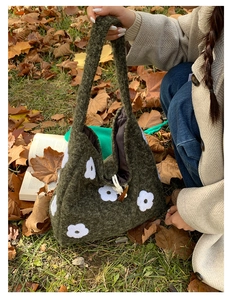 Detail of green knitted tote bag with white floral embroidery and toggle closure