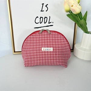Detail of red and white checkered shell cosmetic bag with double zipper and woven label