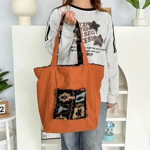 Detail of orange canvas tote with ethnic patterned plush pocket and soft shoulder strap