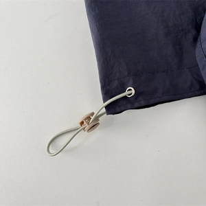 Detail shot of the navy nylon fabric texture and adjustable beige drawstring buckle
