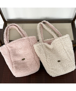 Close-up of plush teddy fleece tote bags in cream and pink with metallic logo detail