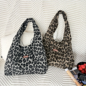Grote luipaardprint pluche shopper met merklabel op een witte minimalistische achtergrond