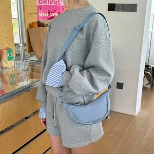Adjustable light blue nylon dumpling bag worn over a casual grey sports set