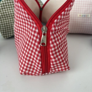 Detail of red and white checkered makeup bag fabric and smooth silver metal zipper