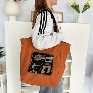 Detail of orange tote bag showing plush ethnic pocket and brand leather label