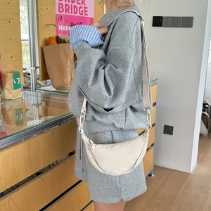 Detail of adjustable strap and plastic hook on cream crescent crossbody bag