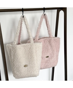 Detail of plush lamb wool tote bags in beige and pink colors with handmade metal logo