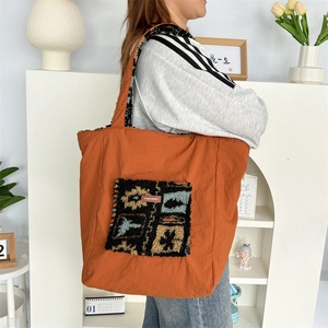 Detail of orange plush tote bag featuring mayrabbit brand patch and durable nylon handles
