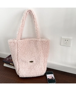 Detail of pink faux fur tote bag showing soft texture and metal logo in a home setting