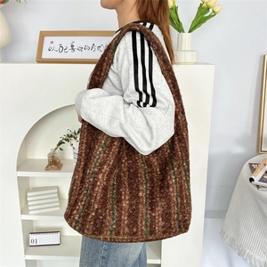 Detail of plush tote bag showing the textured brown fabric and green stripes in daily use