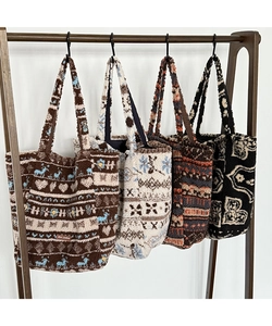 Detailed view of plush tote bags with Nordic reindeer patterns on wooden hangers