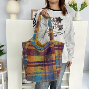 Detail of colorful plaid fleece tote bag showing thick texture and brown logo patch