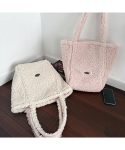 Close-up of plush tote bags in beige and pink with soft fleece texture and metal logo