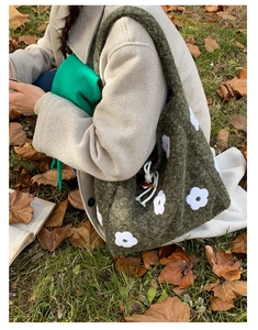 Detail of moss green knit tote bag with white flower appliques and wooden button closure