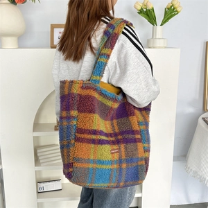 Detail of colorful plaid sherpa tote bag with woven brand label and fuzzy texture