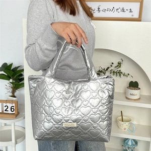 Detail of silver metallic tote bag with 3D heart quilting and branded tag