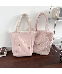 Detail showing two plush pink tote bags with embroidery and fluffy faux fur trim texture