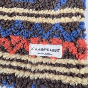 Detail of plush knit tote bag with vintage geometric wavy patterns and brand label
