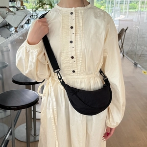 Adjustable black nylon crescent crossbody bag styled on a female model in a minimalist room