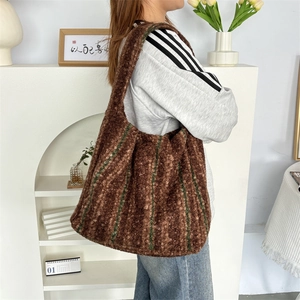 Detail of soft brown plush tote bag with green stripes on integrated wide shoulder strap
