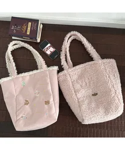 Detail of pink plush tote bags with festive embroidery on a rustic wooden background